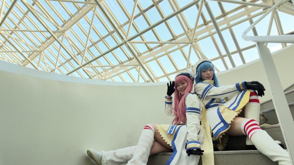 ガラス屋根の下の階段に座るコスプレイヤー2人